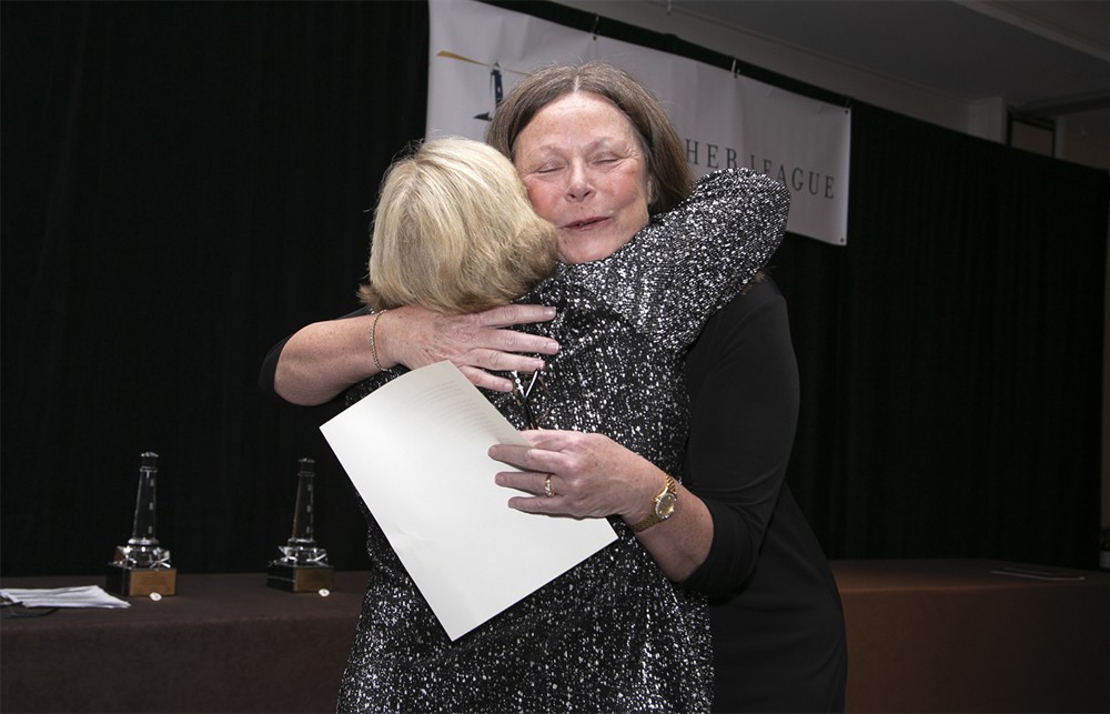 Dee Donatelli hugs Winifred Hayes, Ph.D. on her way to the podium.